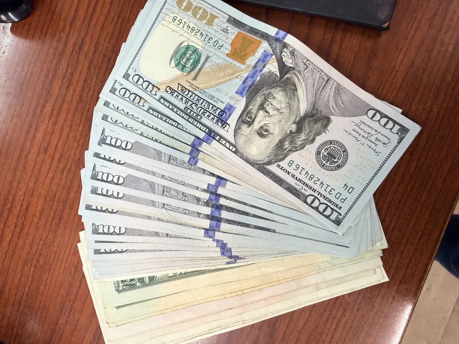 Fanned-out hundred-dollar bills on the shop counter