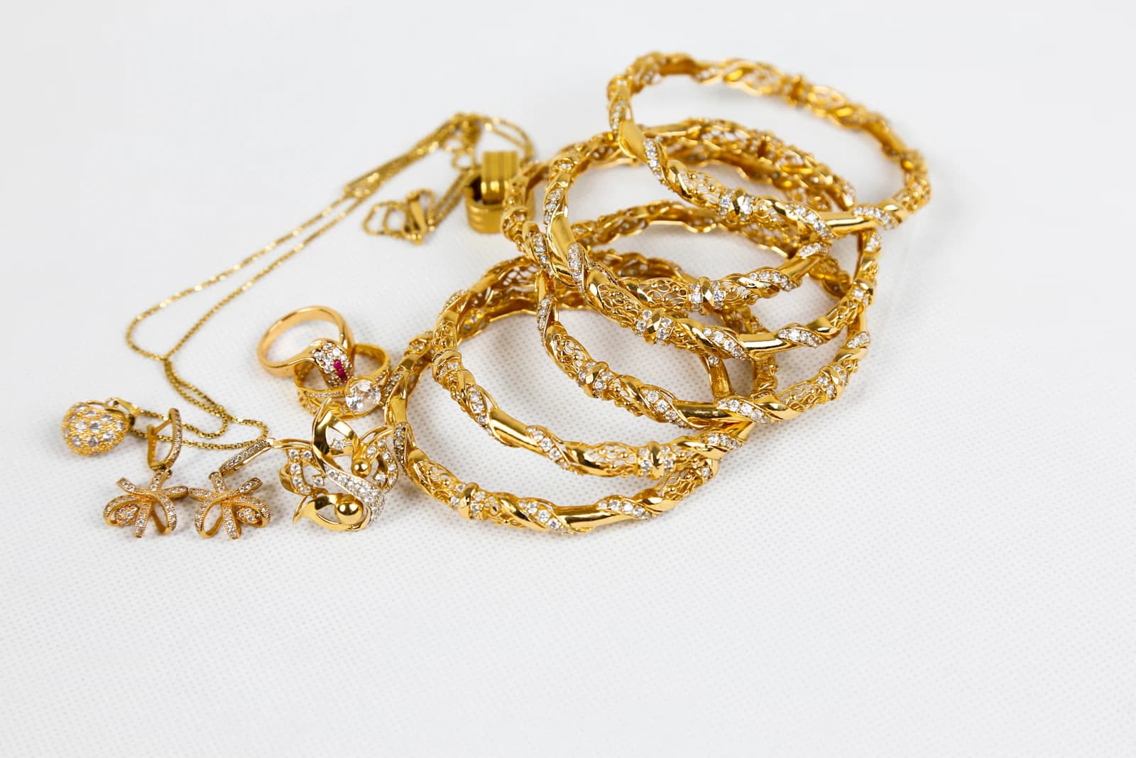 Pile of gold bangles, chains, rings and earrings on a light table